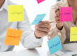 Business people holding similar keyword Post-Its