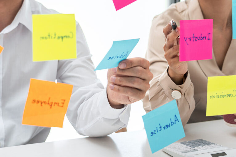 Business people holding similar keyword Post-Its