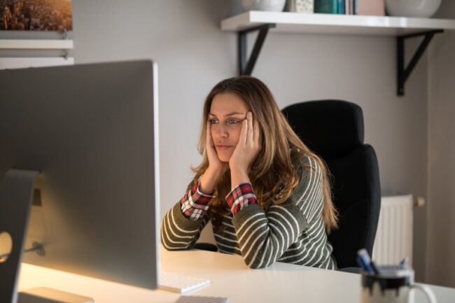 A woman considering a new website in front of her computer. Woman looking thoughtfully at a computer screen.