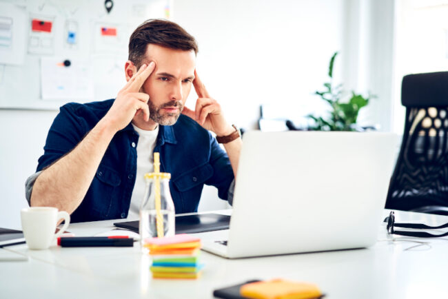 Focused man in front of a laptop Man in front of a laptop working on a free web design