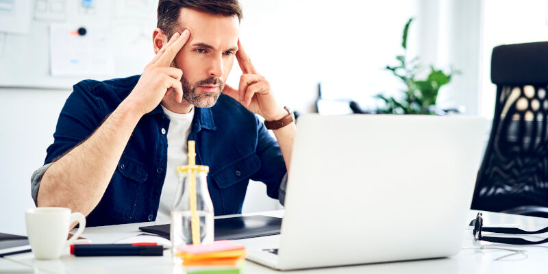 Focused man in front of a laptop Man in front of a laptop working on a free web design