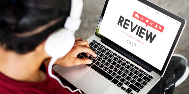 A person at a laptop reading reviews. Person responding to their negative Google reviews.
